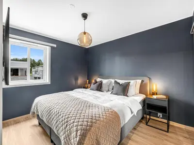 a blue bedroom with a bed and a window at Nice apartment with sea view in Trondheim