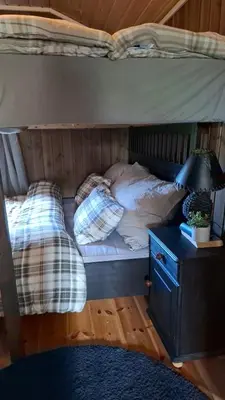 a bunk bed with two pillows and a table with a lamp at Trivelig hytte med innlagt strøm og vann Perfekt for familietur Bilveg helt frem in Rotvolden