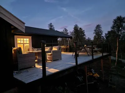 a wooden deck with chairs and a table on it at Trivelig hytte med innlagt strøm og vann Perfekt for familietur Bilveg helt frem in Rotvolden