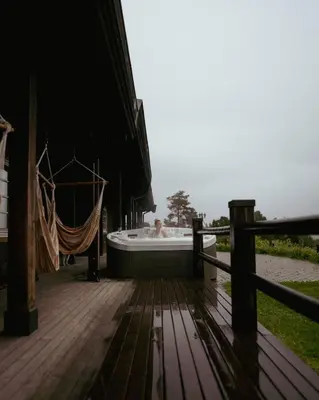 a bath tub on a deck with a person in it at Snerting Ranch Hotel - Comfty and modern Log House in Stokkan