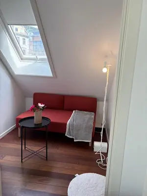 a red couch in a room with a window at In the middle of Bergen City in a real Bergenshus from the 18th Century in Bergen