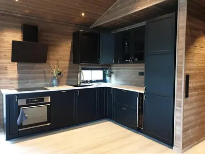 a kitchen with navy blue cabinets and wooden walls at 2 Cabins surrounded by beautiful nature in Stryn