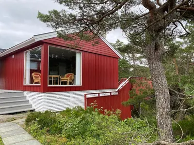 a red and white house with a table and chairs in it at Bjørnafjorden