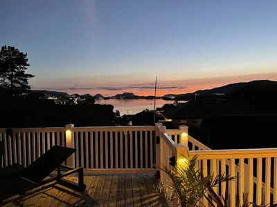 a deck with a view of the ocean at sunset at Casa Oyen in Ålesund