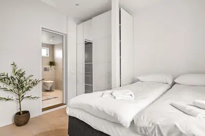 a white bedroom with a large bed and a bathroom at Authentic Bergen Charm in Famous Neighborhood in Bergen
