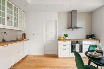 a kitchen with white cabinets and a table with green chairs at Authentic Bergen Charm in Famous Neighborhood in Bergen