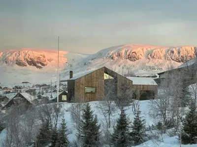 a house in the snow with mountains in the background at Spacious Apartment By Hardangervidda National Park in Ustaoset