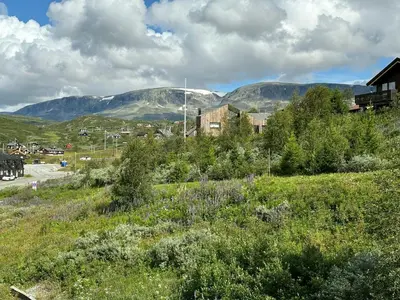 a field with houses and mountains in the background at Spacious Apartment By Hardangervidda National Park in Ustaoset