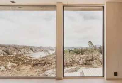 a room with two large windows looking out at a lake at Architect-Designed Cabin Panoramic View in Ervik