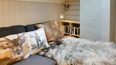 a blanket on a couch with a book shelf at Historic Hunting Lodge By Lake Øyangen in Gålå