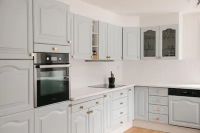 a white kitchen with white cabinets and black appliances at Kommahuset in Ervik