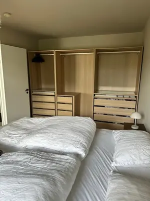 a bedroom with two white beds and empty closets at Elegant city apartment in Bergen- Private outdoor patio and free parking in Bergen