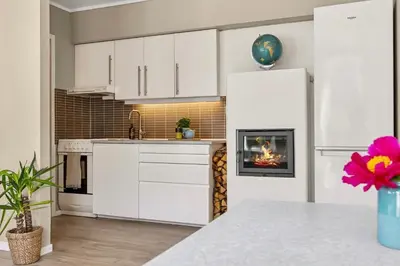a kitchen with white cabinets and a fireplace at Eden Oasis, Bakklandet with Free parking! in Trondheim