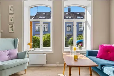 a living room with two chairs and a table and windows at Eden Oasis, Bakklandet with Free parking! in Trondheim