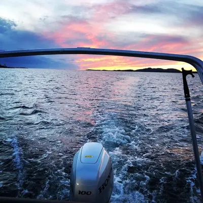 a boat in a body of water with a sunset at Raffelbrygga in Bud