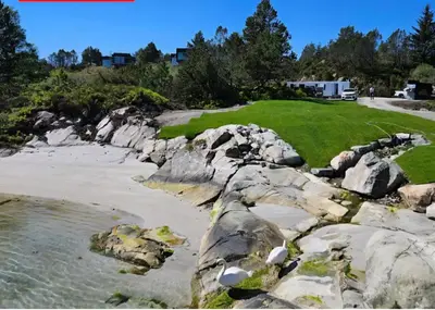 a golf course next to a beach with rocks at Ny feriehytte i skjærgården in Austevoll