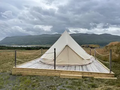 a white tent sitting on a wooden platform in a field at Syndinstøga in Ryfoss