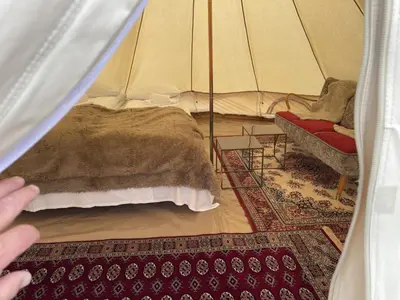 a person reaching into a tent with a bed and a chair at Syndinstøga in Ryfoss