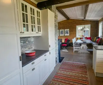 a kitchen with white cabinets and a dining room at Mountain Cabin With Views Of Bonsenås in Tuddal