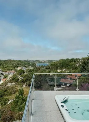 a balcony with a jacuzzi tub on top of a hill at Modern Cabin With Archipelago Views in Bremnes