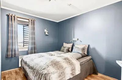 a bedroom with a bed with blue walls and a window at Pellestova - Hafjell in Øyer
