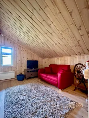 a living room with a red couch and a tv at Indoor hot tub, views & nature, cosy family cabin at Filefjell in Tyinkrysset