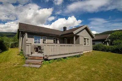 a small house on a field with a grass yard at Cozy house with free parking on the premises in Ringebu