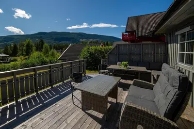 a patio with a table and chairs on a deck at Cozy house with free parking on the premises in Ringebu