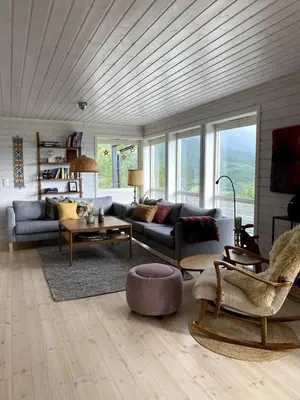 a living room with couches and tables and windows at Great cabin in beautiful nature in Ørsta