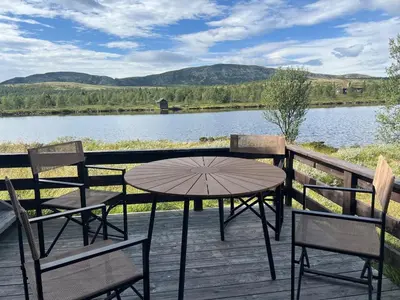 a table and chairs on a deck with a view of a lake at Flaksjøen in Venabygd