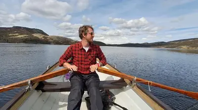 a man sitting in a boat on the water at Flaksjøen in Venabygd