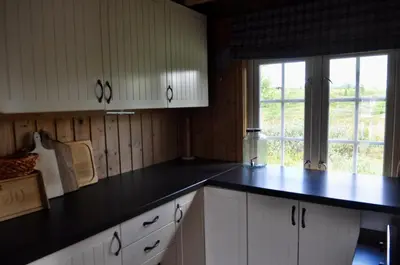 a kitchen with white cabinets and a black counter top at Flaksjøen in Venabygd