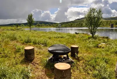 a grill in a field next to a body of water at Flaksjøen in Venabygd
