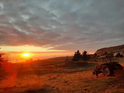 a tractor parked in a field at sunset at Restored Farmhouse By The Sea In Kvalheim in Raudeberg