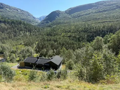 a cabin in the middle of a valley with mountains at Fossen Bratte Mountain home in Eikedalen