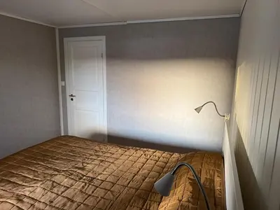 a bedroom with a bed with a lamp next to it at Bergtun's Corner - Sotra Vest in Sekkingstad