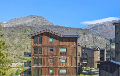 a wooden apartment building with a mountain in the background at 3 Bedroom Awesome Apartment In Hemsedal in Hemsedal