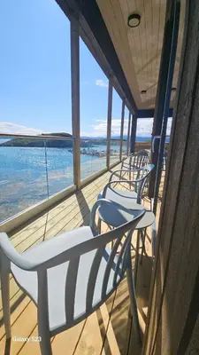 a row of chairs on a balcony with a view of the ocean at Sjåen på Balsnes Gård in Hitra