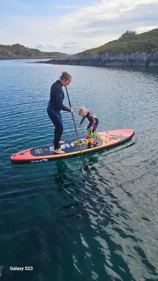 a man and a child on a paddle board in the water at Sjåen på Balsnes Gård in Hitra