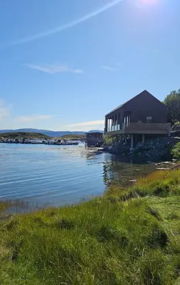 a building on the shore of a body of water at Sjåen på Balsnes Gård in Hitra