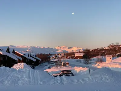 a town covered in snow with mountains in the background at Central on Beitostølen with walking distance to everything in Beitostøl
