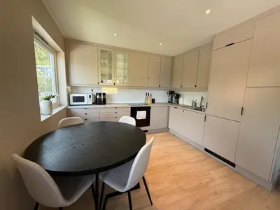 a kitchen with a black table and white cabinets at Moderne 3-roms nær sentrum in Bergen
