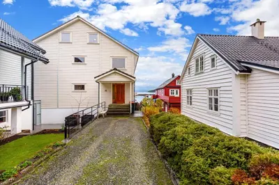 a white house with a red door next to two buildings at Fjordside Escape - Spacious apartment with amazing views in Tysnes