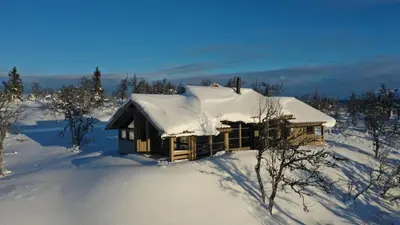 a log cabin covered in snow in a field at Hedda Lenningen - 3 bedroom cabin with view towards Langsua National Park in Etnedal