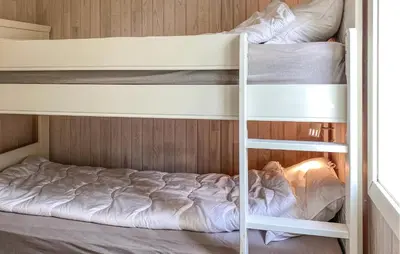 two bunk beds in a bunk room with a ladder at Cozy Apartment In Gurskøy With Sauna in Kjellsund