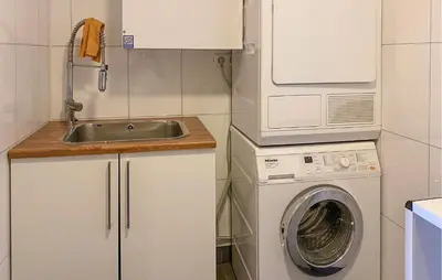 a kitchen with a washing machine and a sink at Cozy Apartment In Gurskøy With Sauna in Kjellsund