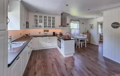 a kitchen with white cabinets and a wooden floor at Amazing Home In Rubbestadneset With Wifi in Rubbestadneset