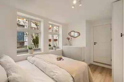 a white room with a bed and two windows at Historisk hus fra 1800-tallet in Bergen