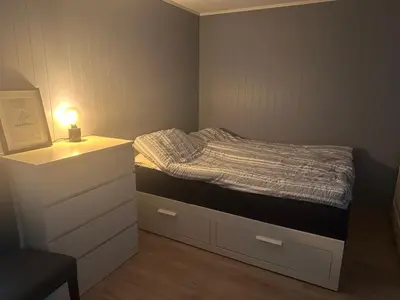 a small bedroom with a bed with a night stand at Flott bolig på Øvre kleppe med fine solforhold og fin uteplass in Askøy