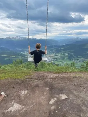 a boy on a swing on top of a hill at Ferieleilighet i Tråstølen in Vossevangen